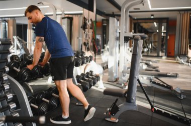 Odaklanmış sporcu dambılları kaldırıyor, rehabilitasyon ve iyileşme için spor yapıyor, güç ve azim gösteriyor.