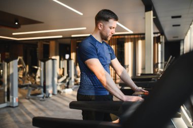 Modern ve iyi donanımlı bir spor salonunda koşu bandı kullanarak rehabilitasyon egzersizlerine konsantre olan kararlı bir sporcu.