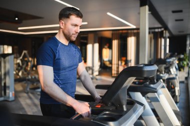 Modern spor salonunda koşu bandına odaklanan erkek sporcu rehabilitasyon ve iyileşme üzerine yoğunlaşıyor.