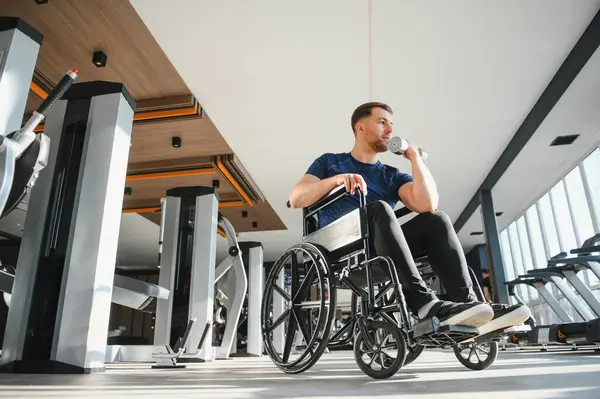Modern spor salonunda ağırlıklarla egzersiz yapan engelli bir adam spor yaparak kapsayıcılığını ve rehabilitasyonunu gösteriyor.