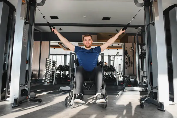 Engelli bir adam modern spor salonunda kablo ağırlıklarıyla egzersiz yapıyor, dayanıklılık ve dayanıklılık gösteriyor, ve kapsayıcı uygunluğu teşvik ediyor.