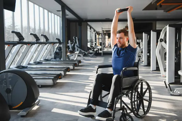 Spor salonunda rehabilitasyon sırasında ağırlık kaldıran engelli bir adam azim ve güç gösteriyor.