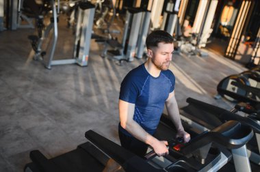 Tekerlekli sandalyedeki adam rehabilitasyon ve spor aletlerini kullanıyor, modern bir spor salonundaki güç ve kararlılığı vurguluyor.