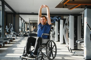 Tekerlekli sandalyede oturan engelli bir adam spor yapıyor ve rehabilitasyon için spor yapıyor.