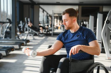 Tekerlekli sandalyede otururken ağırlık kaldıran, rehabilitasyon ve fizik tedavi için spor yapan bir adam.
