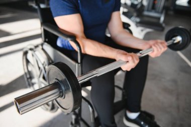 Rehabilitasyon merkezinde fizik tedavi seansı sırasında halterle egzersiz yapan hasta, ulaşılabilir fitness ve iyileşme sürecini destekliyor.