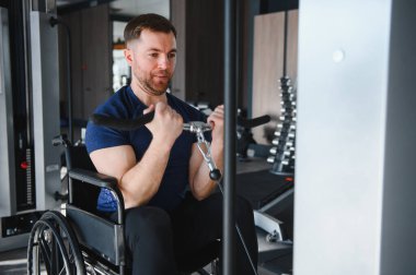 Spor salonunda kablo makinesiyle kol egzersizi yapan, rehabilitasyon ya da spor eğitiminde kararlılık ve güç gösteren kişi