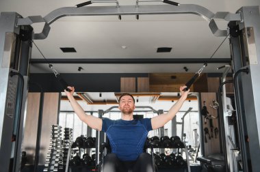 Tekerlekli sandalyedeki adam spor salonunda kablo kullanarak egzersiz yapıyor, dayanıklılık ve dayanıklılık gösteriyor,