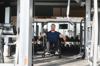 Modern erişilebilir spor salonunda kablo sıra makinesiyle egzersiz yapan engelli kişi, güç ve kararlılık gösteriyor