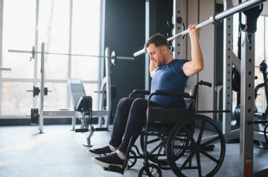 Spor salonunda halterle egzersiz yapan, rehabilitasyon ve spor eğitimi sırasında esneklik ve güç gösteren biri.