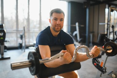 Özürlü bir kişi ez bar kullanır, spor salonunda pazı egzersizi yapar, rehabilitasyon ya da fizyoterapi sırasında