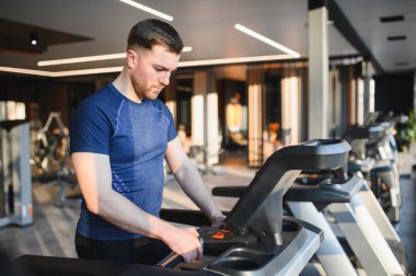Koşu bandı kullanan, parlak, modern bir spor salonunda rehabilitasyon gören, iyileşme ve zindeliğe kendini adamış bir sporcu.
