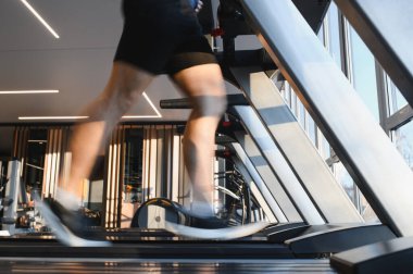Spor salonunda koşu bandında koşan, spor rehabilitasyonuna ve fizik tedaviye odaklanan erkek atletin bulanık bacakları.