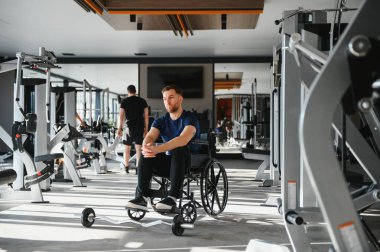 Özürlü genç bir adam spor salonunda egzersiz yapıyor, uyum sağlayarak sağlıklı bir yaşam tarzı sergiliyor.