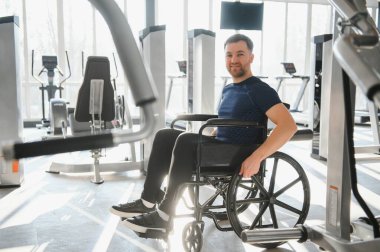 Spor salonunda tekerlekli sandalye egzersizi yapan, engelliler için sağlık, spor ve sağlık hizmetlerini destekleyen bir adam.