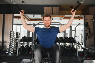 Modern spor salonunda kablo ağırlığıyla egzersiz yapan engelli bir adam rehabilitasyon eğitiminde kararlılık ve güç gösteriyor.