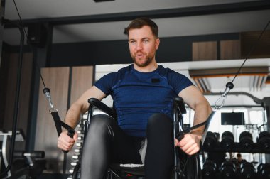 Tekerlekli sandalyedeki adam vücut egzersizi için kablo kullanıyor. Spor salonunda dayanıklılık ve dayanıklılık gösteriyor.