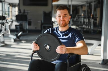 Spor salonunda ağırlık plakası ile egzersiz yapan, rehabilitasyon ve iyileşme için kapsayıcılık ve adaptif eğitim sergileyen kişi