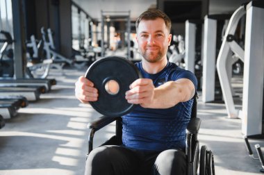 Engelli bir sporcu, modern bir spor salonunda tekerlekli sandalyede otururken ağırlık egzersizi yapıyor ve dayanıklılık ve dayanıklılık gösteriyor.