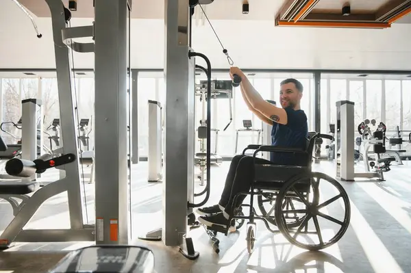 Spor salonundaki rehabilitasyon egzersizleri sırasında Lat makinesini kullanan hasta fiziksel kısıtlamaların üstesinden gelmek için kendini adamış ve gücünü göstermiştir.