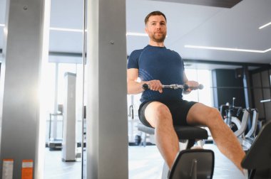 Hasta, oturma kablo sırası makinesinde rehabilitasyon egzersizleri yapıyor. Spor salonunda güç ve iyileşme üzerine yoğunlaşıyor.