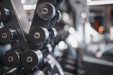 Metal halterler arka arkaya dizilmiş. Bulanık spor salonu ortamında güç antrenmanlarına hazır. Vücut geliştirme ve sağlık.