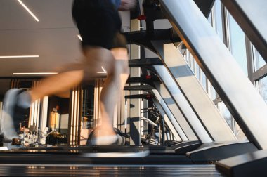 Spor salonundaki koşu bandında koşan, spor antrenmanlarına ve rehabilitasyona odaklanan erkek bacaklarının bulanık hareketi.
