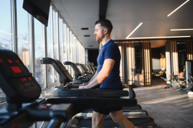 Modern bir rehabilitasyon merkezinde koşu bandında yürürken fizik tedavi gören hasta iyileşme ve güce odaklanıyor.