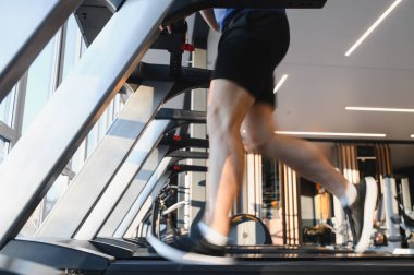 Modern bir spor salonundaki rehabilitasyon egzersizleri sırasında koşu bandında koşan hasta iyileşme sürecine odaklanıyor ve kardiyo egzersizleriyle güç kazanıyor.