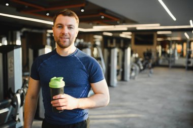 Sallanan şişeyi tutan sporcu, rehabilitasyon sırasında dinleniyor, iyileşme sürecine odaklanıyor ve kondisyonunu koruyor.