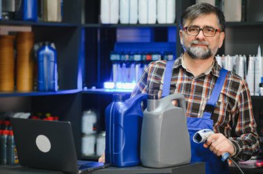 Satış elemanı, oto yedek parça mağazasında barkod tarayıcısıyla motor yağını tarıyor, envanteri yönetiyor ve araba bakım gereksinimleri olan müşterilere yardım ediyor.