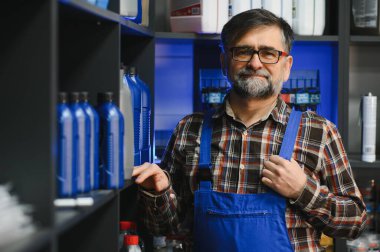 İyi organize edilmiş bir rafta motor yağı şişelerini sunan kendine güvenen bir satıcı, çalışkan bir oto yedek parça mağazasında özenle çalışıyor.