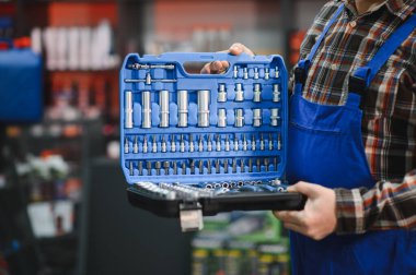 Tamirci, araba bakımı ve onarımı için geniş bir ekipman seçimi sunarak, bir oto yedek parça mağazasında profesyonel bir alet kiti gösteriyor