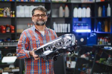 Araba yedek parça dükkanında yeni bir far gösteren pazarlamacı çok çeşitli araba parçaları sunuyor.
