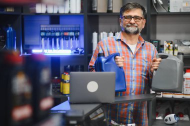 Bir oto yedek parça dükkanında tezgahta dururken farklı motor yağı şişelerini gösteren bir satıcı.