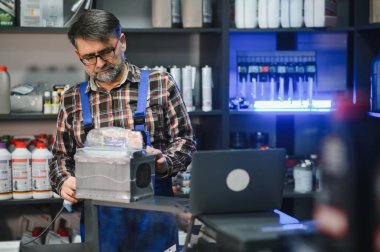 Satıcı bir oto yedek parça dükkanında çalışırken barkod tarayıcı ile bir araba parçasını tarıyor.