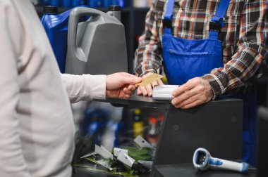 Müşteri, araba parçası dükkanında kredi kartıyla ödeme yapmış. Satıcının da yardımıyla.