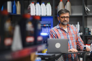 Satış elemanı dizüstü bilgisayar ve barkod tarayıcı kullanıyor, oto yedek parça deposundaki envanter ve satışları yönetiyor.