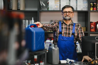Satış elemanı bir oto yedek parça mağazasında müşterilere yardımcı olurken bir kutu motor yağı sunuyor, otomotiv ürünlerinde uzmanlık sergiliyor