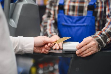 Müşteri, oto yedek parça dükkanında kredi kartıyla ödeme yapıyor. Satıcının da yardımıyla.
