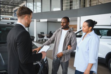 Profesyonel bir araba satıcısı Afrikalı Amerikalı bir çifte kontrat gösteriyor. Modern bir galeriden yeni bir araba alıyor.