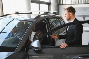 Profesyonel araba satıcısı, yeni otomobilin özelliklerini Afro-Amerikan çifte sunuyor. Modern bayilikte mükemmel müşteri hizmetleri sunuyor.