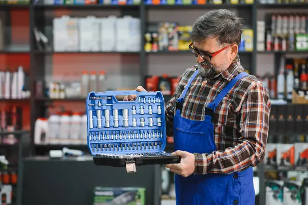 Bir oto yedek parça mağazasında profesyonel bir soket anahtarı tutan tamirci, müşterilere yardım ve uzmanlık sunuyor
