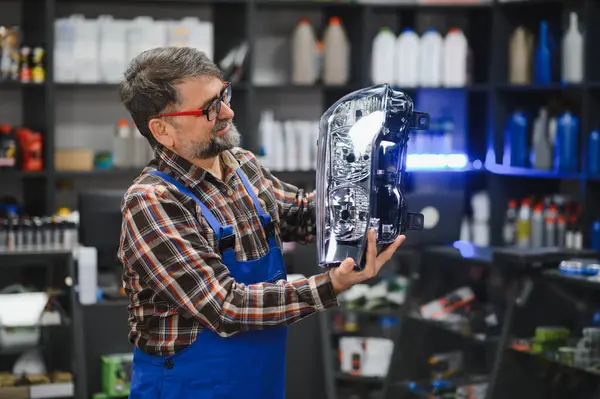 Araba yedek parça satıcısı müşteriye farını gösteriyor, araba tamiratı için uzman tavsiyesi ve yardım sağlıyor