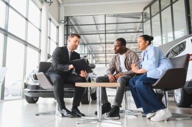 Satıcı, kontrat detaylarını Afrikalı Amerikalı çifte açıklıyor. Modern bayilikten yeni bir araba alıyorlar.