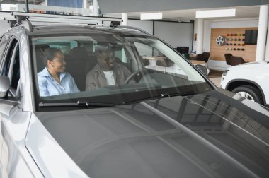 Yeni bir galeride yeni bir araba denemenin zevkini çıkaran mutlu çift, yaklaşan alışverişleri için heyecanlı.