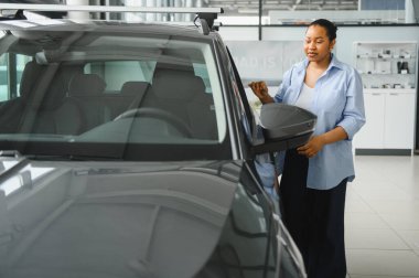 Müşteri otomobil galerisinde yeni bir arabayı inceliyor. Bir sonraki aracı için çeşitli satın alma seçenekleri ve özelliklerini inceliyor.