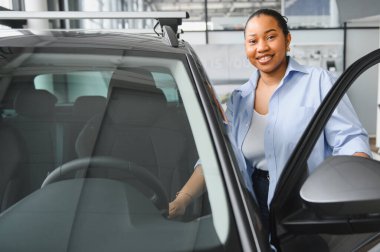 Araba galerisinde mutlu müşteri inceleme aracı. Direksiyona dokunmak, kapıyı açmak ve gülümsemek.