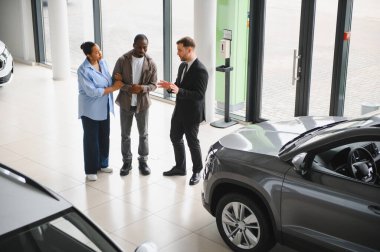 Araba satıcısı, modern araba galerisinde Afro-Amerikan çifte yeni arazi aracı sunuyor.