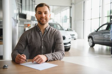 Modern bir galeride yeni bir araba almak için kontrat imzalayan mutlu bir müşteri.